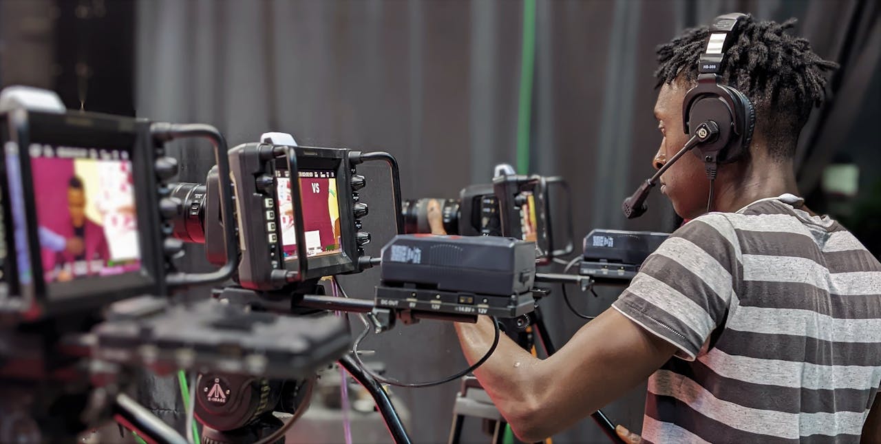 A videographer adjusts camera equipment during a live broadcast in a studio setting.